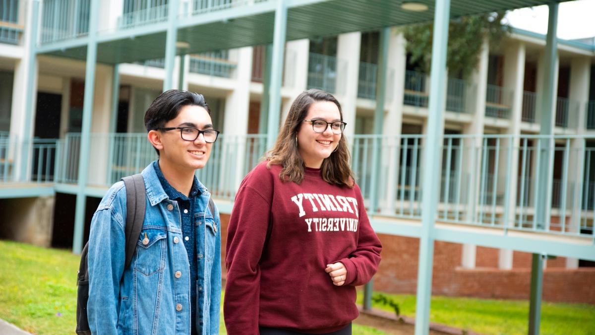 two 学生 walk next to a bridge between two residence halls