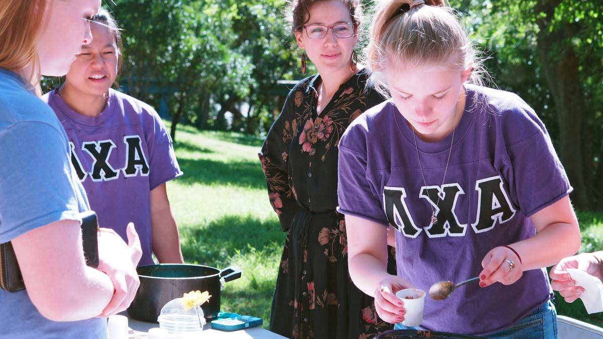 two sorority members serve chili from a crock pot